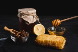 A display of honey, lemon wedges, a cinnamon stick, and numerous honeycomb sections artistically arranged.